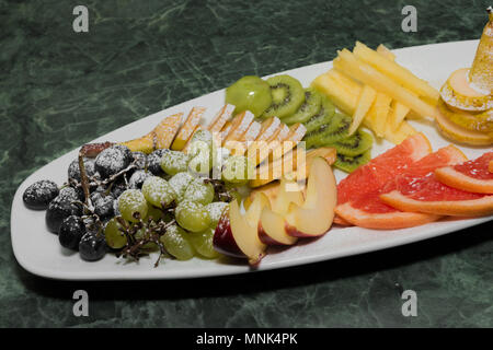 Geschnittenes Obst auf einem weissen Teller, Trauben, Kiwi, Orange, Birne Stockfoto