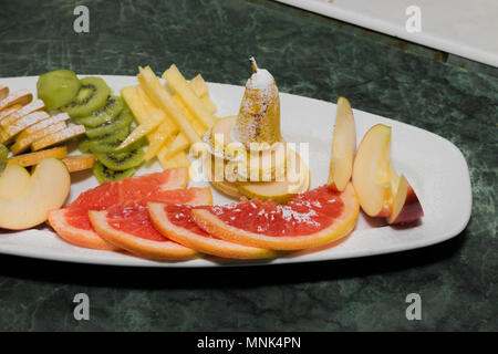 Geschnittenes Obst auf einem weissen Teller, Trauben, Kiwi, Orange, Birne Stockfoto