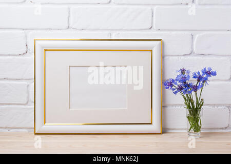 Gold frame Mockup mit blauen Kornblumen in der einfachen Glas Vase. Leeren Rahmen mock up für Präsentation Artwork. Vorlage framing für moderne Ein Stockfoto