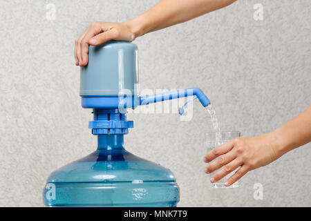 Nahaufnahme der Hand gießt Wasser in Glas von der Flasche Stockfoto