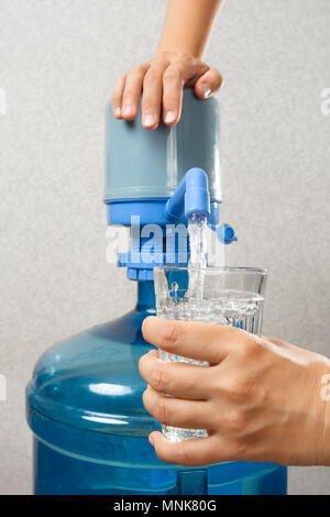 Hände von Frau gießen sauberes Wasser in Glas von der Flasche mit Pumpe Stockfoto