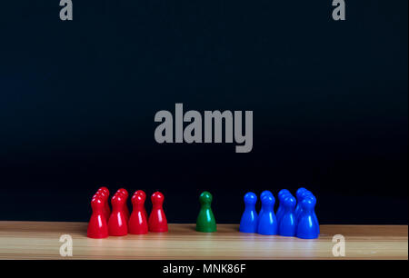 Schachfiguren in drei Farben auf einem Holztisch mit schwarzem Hintergrund Stockfoto