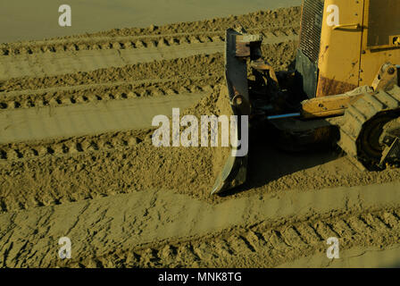 Nahaufnahme, Detail, Ziehklinge von gelben Bulldozer schieben Sand über Anschluss Aufdrucke auf Gebäude Baustelle, blur Stockfoto