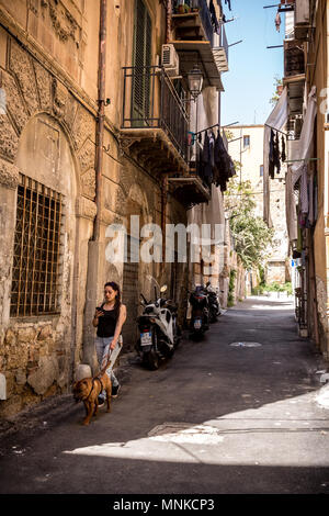 Eine junge Frau wird zu einer typischen Gasse der Altstadt Ballaro Bereich von Palermo, Sizilien vom 24. April 2018. Stockfoto