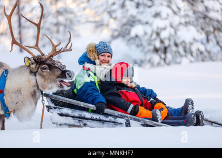 Die Familie der Mutter und des kleinen Mädchens auf Rentier Safari im Winter Wald in Lappland Finnland Stockfoto