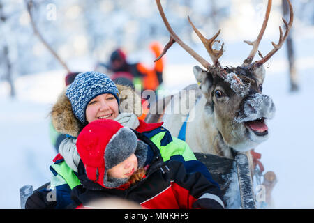 Die Familie der Mutter und des kleinen Mädchens auf Rentier Safari im Winter Wald in Lappland Finnland Stockfoto