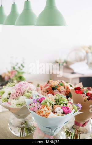 Floristik Konzept. Vier Bouquet von schönen Blumen auf grau Tabelle. Frühling Farben. Die Arbeit der Florist in einem Blumenladen. Stockfoto