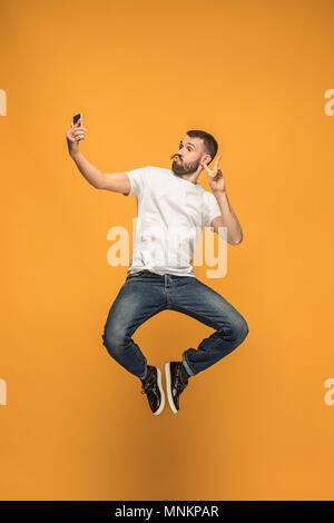 Zeit selfie zu nehmen. Volle Länge des gutaussehenden jungen Mann unter selfie beim Springen Stockfoto
