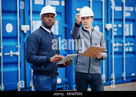 Zwei Ingenieure tracking Container mit einem Klemmbrett und digitale Tablet beim Stehen auf einem großen kommerziellen Schifffahrt dock Stockfoto
