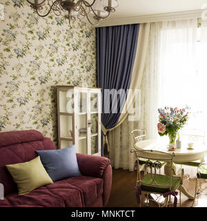 Sonniges Wohnzimmer mit großen Blumenstrauß auf runden Tisch, Interieur im Stil der Provence Stockfoto