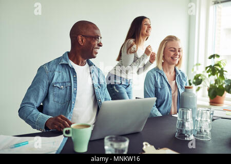 Afrikanischen Geschäftsmann mit einer Gruppe von Kollegen während einer Sitzung gemeinsam lachen in einem modernen Büro Stockfoto