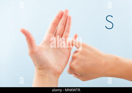 Fingerspelling Alphabet. Weibliche Hände isoliert auf blauem Hintergrund zeigen, Taubstumme BSL Buchstaben S. Stockfoto