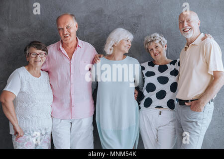 Lächelnde ältere Leute um Spaß zu haben, sich gegen eine Betonwand Stockfoto