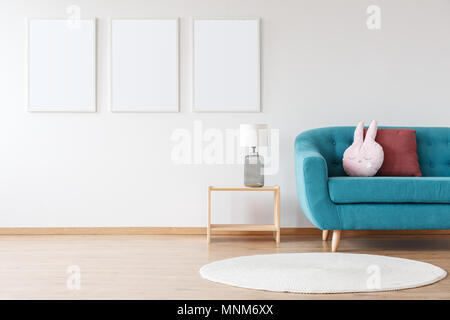 Mockup von weißen Plakaten und Lampe auf hölzernen Hocker in Kinderzimmer mit blauen Sofa und weissen Teppich Stockfoto