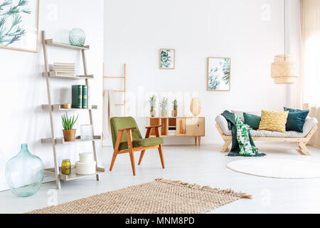 Dekoratives Glas Vase neben Regal mit Werk in farbenfrohen Wohnzimmer mit Ananas auf Schrank Stockfoto