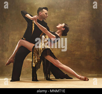 Tanz Ballroom Couple in Gold Kleid tanzen auf Studio Hintergrund. Stockfoto