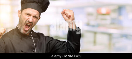 Senior cook Mann mit Küchenchef hat glücklich und aufgeregt feiert Sieg zum Ausdruck großer Erfolg, Leistung, Energie und positive Emotionen. Feiert neuen Jo Stockfoto