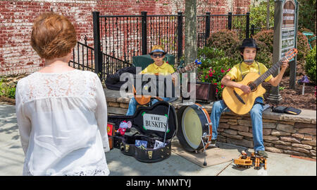 Zwei Jungen Straßenmusik mit Gitarren auf der Main Street in Blowing Rock, NC, USA, Beobachten von einer rothaarigen Frau, die Zuschauer. Stockfoto