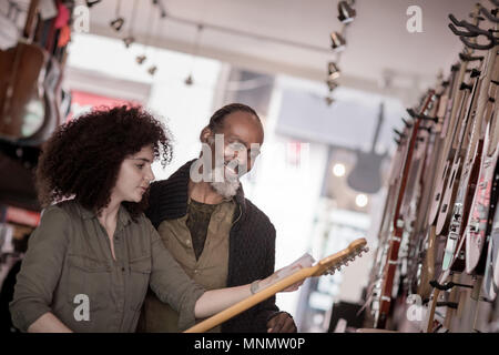 Inhaber kleiner Unternehmen hilft Kunden in einem Guitar Store Stockfoto