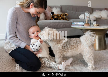 Mutter und Tochter (18-23 Monate) spielen mit Hund im Wohnzimmer Stockfoto