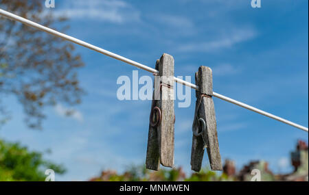 Alte hölzerne Wäscheklammern auf eine Wäscheleine an einem sommerlichen Nachmittag gegen ein strahlend blauer Himmel Stockfoto