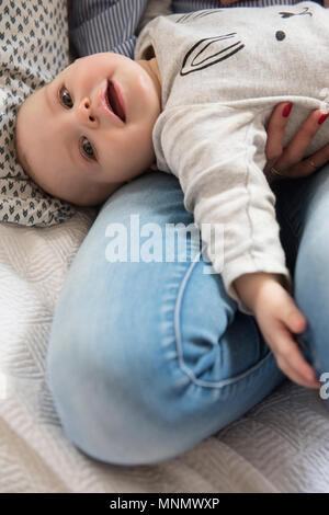 Baby Girl (12-17 Monate) liegend auf Mama's Schoß Stockfoto