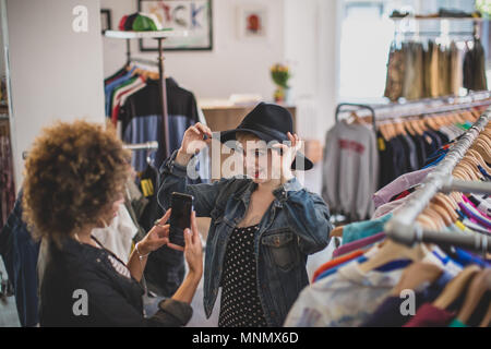 Tausendjährige versuchen auf einen Hut in einem vintage Clothing Store Stockfoto