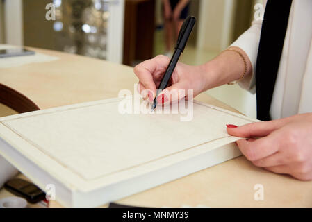 Die Hand des Mädchens hält einen Stift auf ein leeres Blatt Papier. Stockfoto
