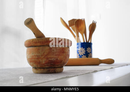 Nahaufnahme der alte hölzerne Mörser mit Pistill innen am weißen Tisch mit grau Tischdecke. Stockfoto