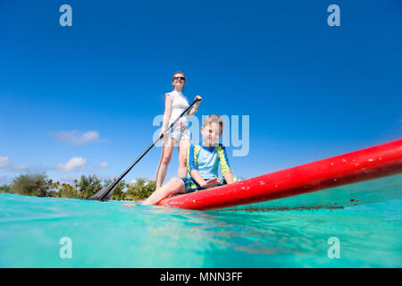 Mutter und Sohn paddeln auf Stand up Paddle Board im tropischen Ozean Stockfoto