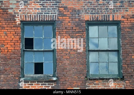 Zwei gebrochene Windows auf einem alten industrialo rotes Backsteingebäude im Warehouse District von New Orleans. Stockfoto
