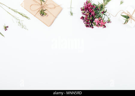 Obere Grenze Rahmen aus einem Blumenstrauß, wilde Kräuter, Geschenke verpackt in braunem Papier und gebunden mit Jute Seil. Rustikal Eingerichteten flach Zusammensetzung mit einem leeren Stockfoto