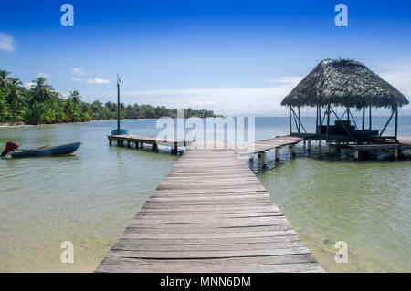 BOCAS DEL TORO, PANAMA - 20. APRIL 2018: Im freien Blick auf die hölzerne Seebrücke mit einer Hütte im Star Fish Beach befindet sich auf Bocas del Toro Insel mit einem Boot warten auf tourits Stockfoto