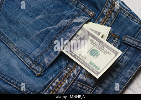 Banknoten eines hundert Dollar mit einem Porträt von Franklin peep aus der Tasche der Jeans Hose. Geld in der Tasche, Geld sparen, pocket expens Stockfoto