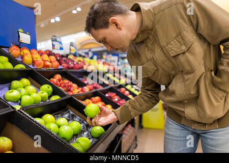 Viele verschiedene Sorten Äpfel auf dem Regal im Supermarkt Kisten in Gang, Supermarkt, Mann, Person, Kunden halten Sie Granny Smith Stockfoto