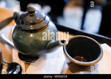 Nahaufnahme der Teekanne, Schale in japanischen traditionellen asiatischen Restaurant oder Cafe mit Eingang auf dem Tray Table, Löffel, Gabel Stockfoto