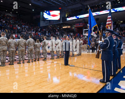 Master Sgt. Alyson Jones, US Air Force Band von Sänger, singt die Nationalhymne als Mitglieder der Wright-Patterson Air Force Base Ehrengarde die Farben, und Flieger aus WPAFB entfalten eine große Garnison - Größe amerikanische Flagge während der pregame Zeremonien vor der ersten vier NCAA Turnier an der Universität von Dayton Arena in Dayton, Ohio, 14. März 2018. Während Halbzeit Ereignisse des Spiels, Generalleutnant Robert McMurry jr., Air Force Life Cycle Management Center Commander, den Eid der Rekrutierung zu verspäteter Eintragung Personal verabreicht. Stockfoto