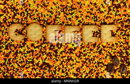 Kaffee. Das Wort von den essbaren cracker Buchstaben liegt auf der verglasten Pulver. Eine große Anzahl von süßen, bunten Perlen von sehr kleinen Größe für die Dekoration Stockfoto