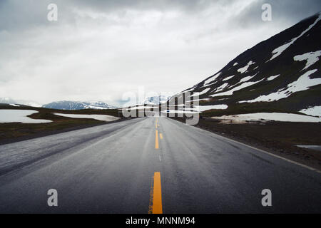 Malerischer Blick auf der E6 in Norwegen mit Schnee bedeckten Bergen bedeckt an einem bewölkten Tag im Sommer. Stockfoto