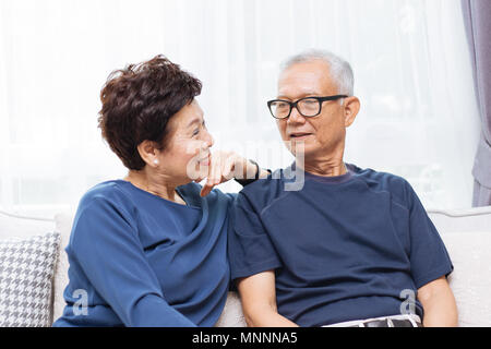 Romantische senior asiatischen Paar lachen und sitzt auf einem Sofa zu Hause Stockfoto