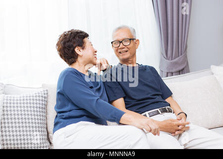 Romantische senior asiatischen Paar lachen und sitzt auf einem Sofa zu Hause Stockfoto