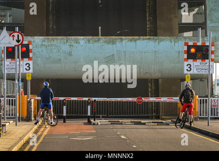 Zwei Radfahrer auf Barrieren auf die Bucht von Cardiff barrage warten bis die Straße Brücke wird abgesenkt Stockfoto