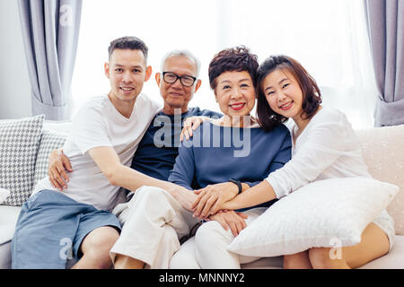 Asiatische Familie mit erwachsenen Kindern und älteren Eltern entspannt auf einem Sofa zu Hause zusammen Stockfoto