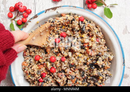 Schritt für Schritt 2/7: Winter berry Futterhäuschen mit Ausstecher. Mix Nüsse, Samen und Beeren mit geschmolzenem Fett. Gut umrühren, um sicherzustellen, dass Fett deckt alle. Stockfoto