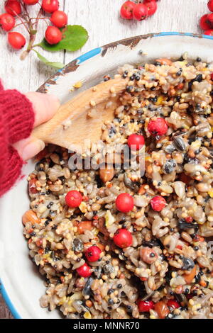 Schritt für Schritt 2/7: Winter berry Futterhäuschen mit Ausstecher. Mix Nüsse, Samen und Beeren mit geschmolzenem Fett. Gut umrühren, um sicherzustellen, dass Fett deckt alle. Stockfoto