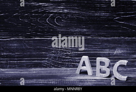 Alphabet aus Holz auf dem Hintergrund einer Platine, Ebenholz. Konzept von Bildung, Englisch. Englische Briefe, Retro. Stockfoto