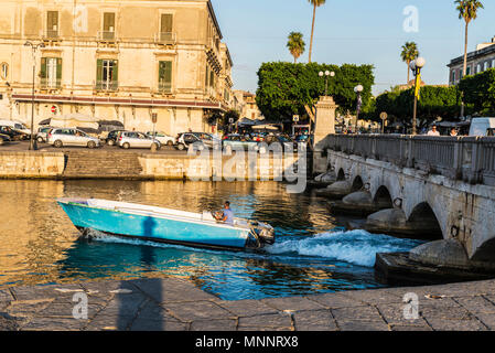 Siracusa, Italien - 17. August 2017: der Mann, der das Segeln in ein Boot neben der alten Brücke, links von Syrakus und Ortigia mit klassischen Gebäuden und Menschen d Stockfoto