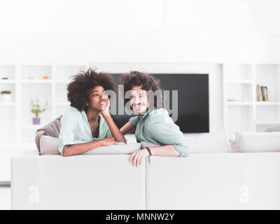 Jungen multiethnischen Paar sitzt auf einem Sofa im Wohnzimmer Stockfoto