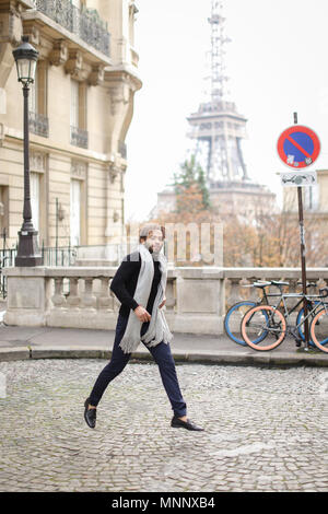 Afro-amerikanischer Mann in der Nähe von Straße und Fahrrad mit dem Eiffelturm im Hintergrund laufen, das Tragen von grauen Schal und schwarzen Pullover. Stockfoto