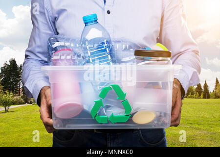 Die Person in der Hand tragen Recycling Container voller Plastikflaschen Stockfoto